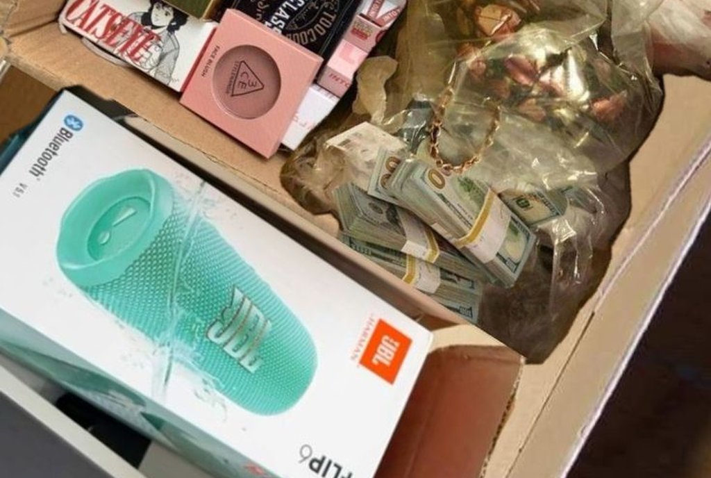 Caixa de papelão com um celular lacrado e outros produtos variados ainda nas embalagens